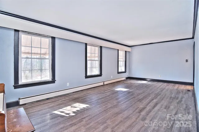 an empty room with wooden floor fireplace and windows