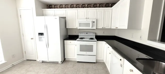 a kitchen with a refrigerator and white cabinets