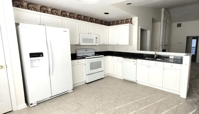 a kitchen with white cabinets and white appliances