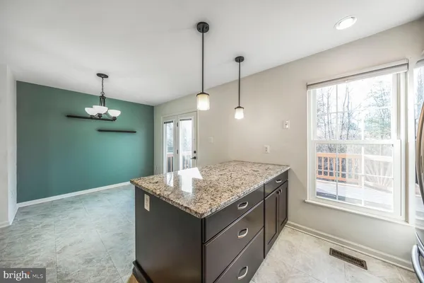 a kitchen with kitchen island a chandelier wooden cabinets and a chandelier