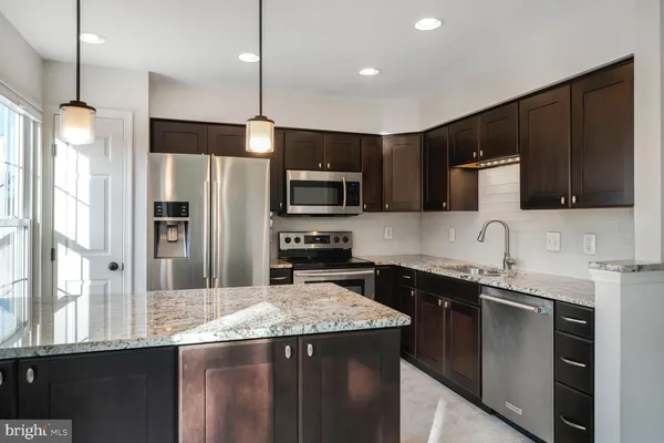 a kitchen with a sink a center island stainless steel appliances and cabinets