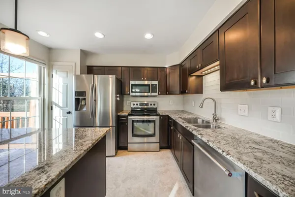 a kitchen with stainless steel appliances granite countertop a sink a stove and a refrigerator