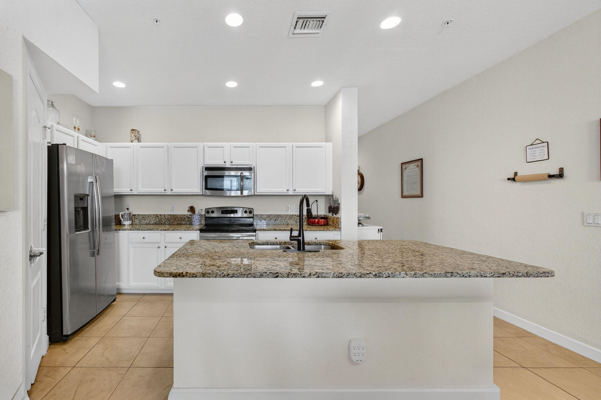 9440 Southwest Merlin Court Stuart, FL 34997 - Photo 12 of 54 a kitchen with stainless steel appliances granite countertop a sink refrigerator and cabinets