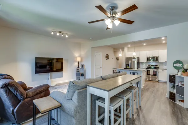 a living room with furniture kitchen view and a flat screen tv