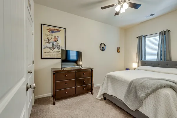 a bedroom with a bed and a flat tv screen on dresser