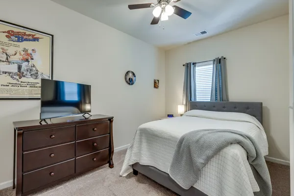a bedroom with a bed and a flat tv screen on dresser