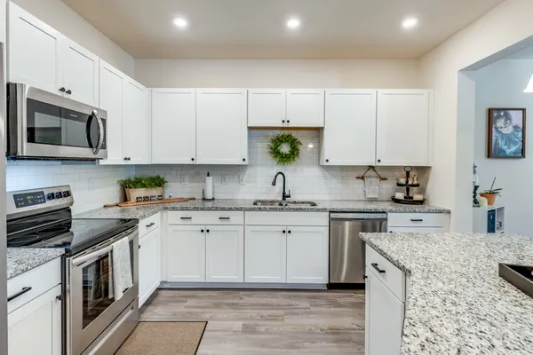 a kitchen with stainless steel appliances granite countertop a stove top oven a sink a microwave and cabinets