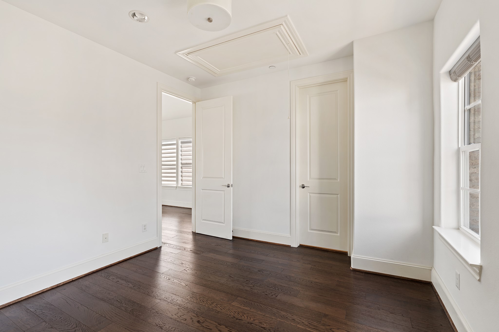 1314 Hunters Meadow Lane Houston, TX 77055 - Photo 21 of 37 Bright room with hardwood floors, white walls, and ample natural light from large windows. Features two doors and recessed ceiling lights. Ideal for a bedroom or office space.