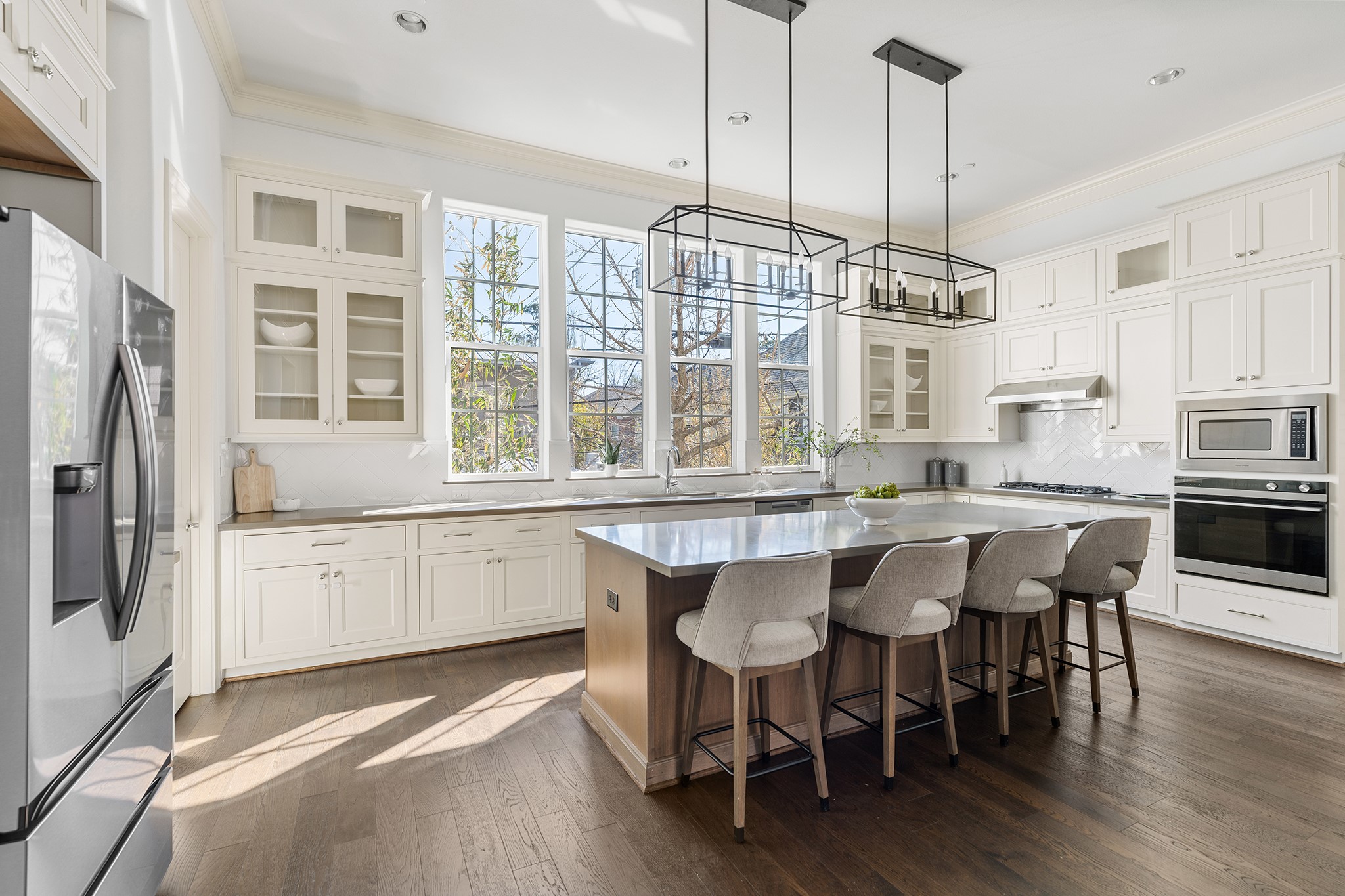 1314 Hunters Meadow Lane Houston, TX 77055 - Photo 27 of 37 This bright kitchen features white cabinetry, a large island with seating, stainless steel appliances, and chic pendant lighting. Large windows provide ample natural light, complementing the elegant hardwood floors.