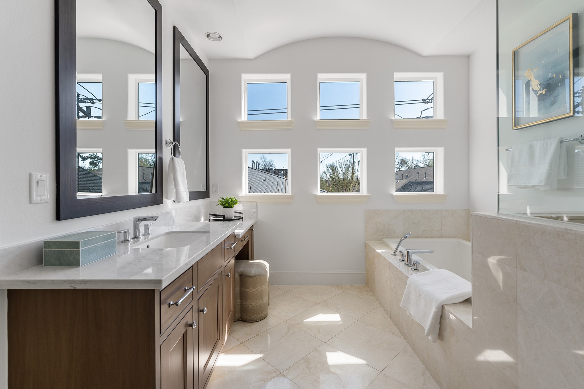 1314 Hunters Meadow Lane Houston, TX 77055 - Photo 28 of 37 Bright, modern bathroom with a sleek double vanity and a luxurious soaking tub. Natural light floods in through multiple square windows, highlighting the elegant tile flooring and clean design.