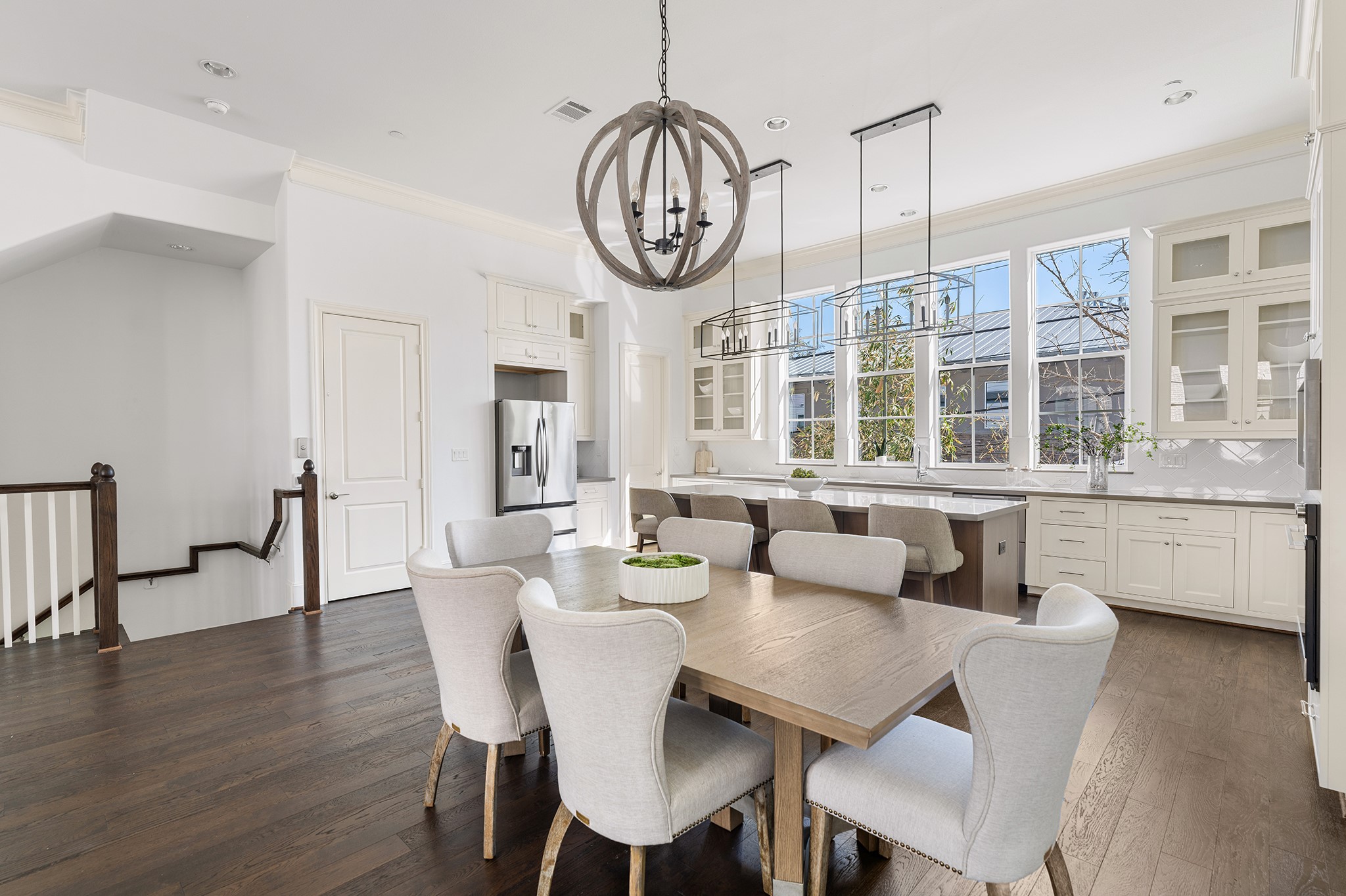 1314 Hunters Meadow Lane Houston, TX 77055 - Photo 30 of 37 This spacious kitchen and dining area features elegant hardwood flooring, ample natural light from large windows, and modern fixtures. The room includes a stylish chandelier, a sizable island with seating, and plenty of white cabinetry for storage, creating a bright and inviting space perfect for entertaining.