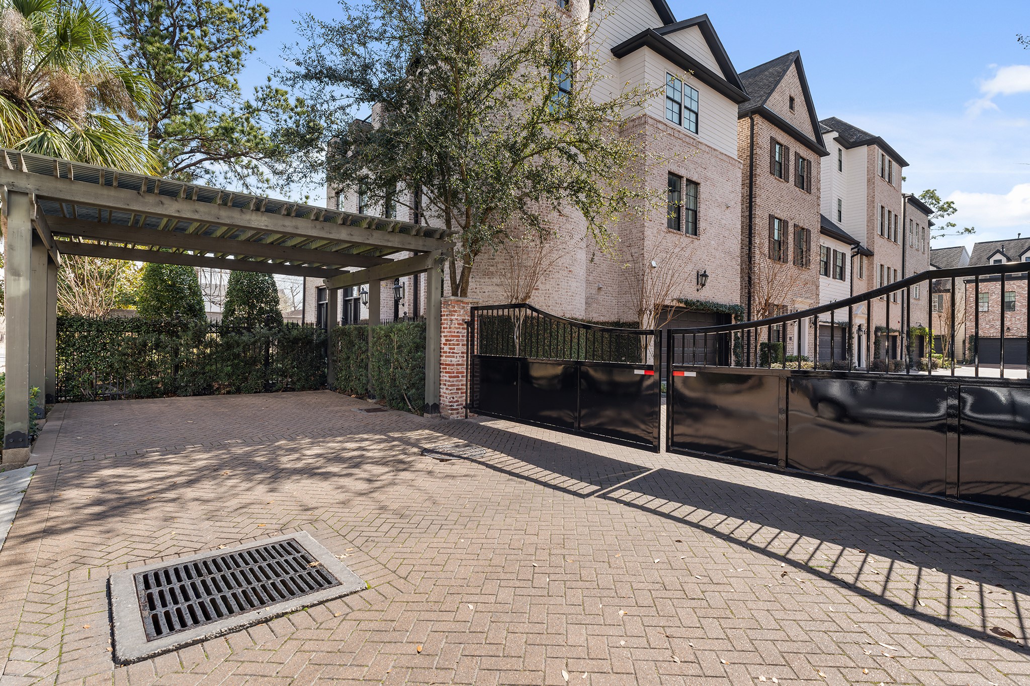 1314 Hunters Meadow Lane Houston, TX 77055 - Photo 36 of 37 This photo showcases the paved driveway, guest parking pergola and the impressive gate leading to the community,. Lush greenery and trees add to the appeal, providing a welcoming and secure environment.