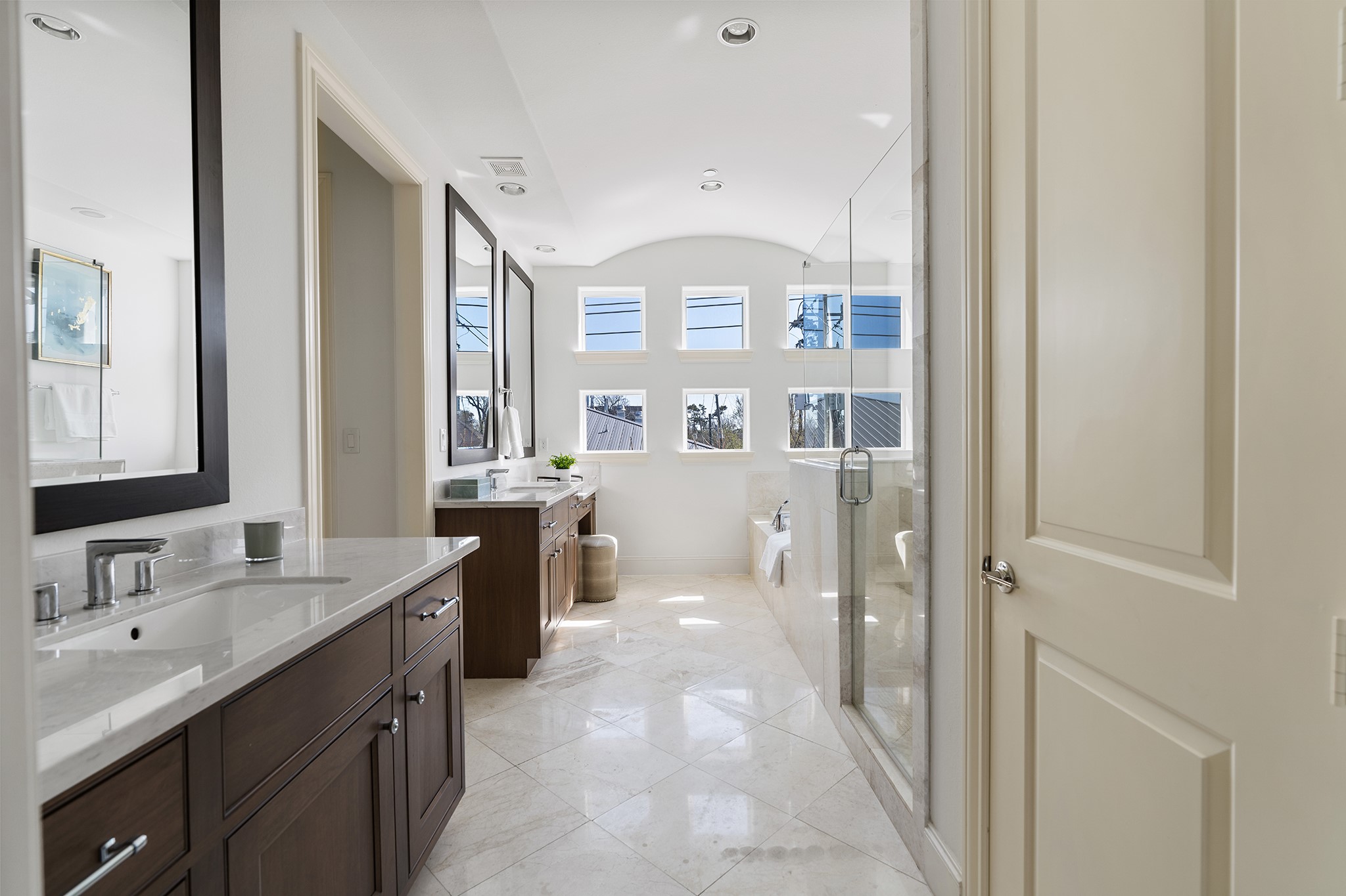1314 Hunters Meadow Lane Houston, TX 77055 - Photo 10 of 37 This spacious, well-lit bathroom features double sinks with elegant dark wood cabinetry, a large glass-enclosed shower, and a luxurious soaking tub. Bright windows provide ample natural light, complementing the modern and clean design.