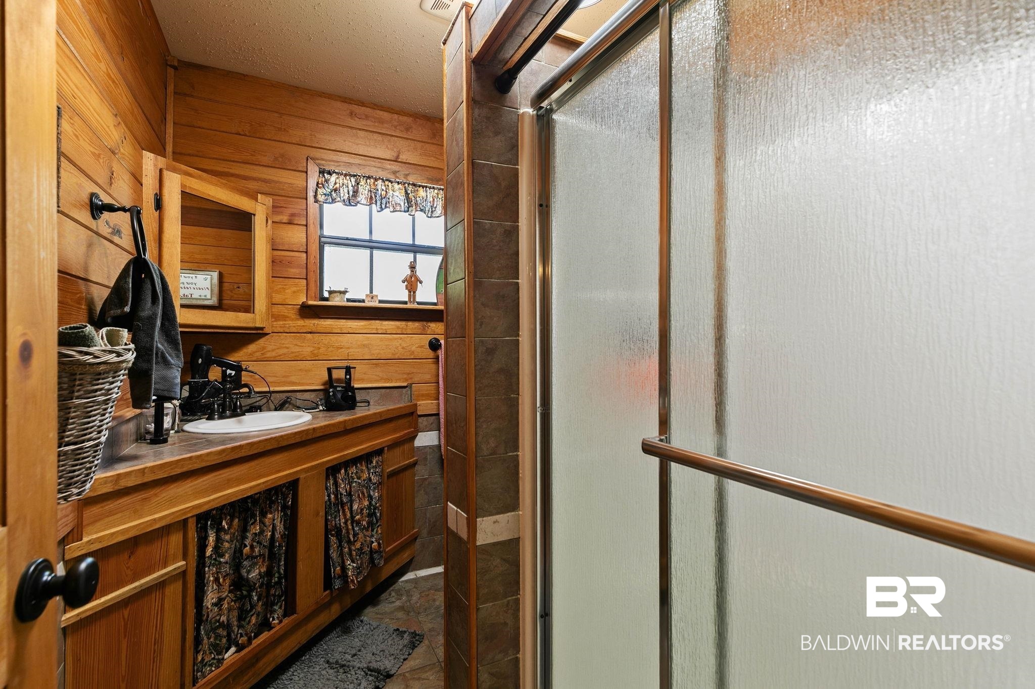 724 Rowell Lane Brewton, AL 36426 - Photo 23 of 40 Bathroom with a stall shower, wooden walls, vanity, and a textured ceiling
