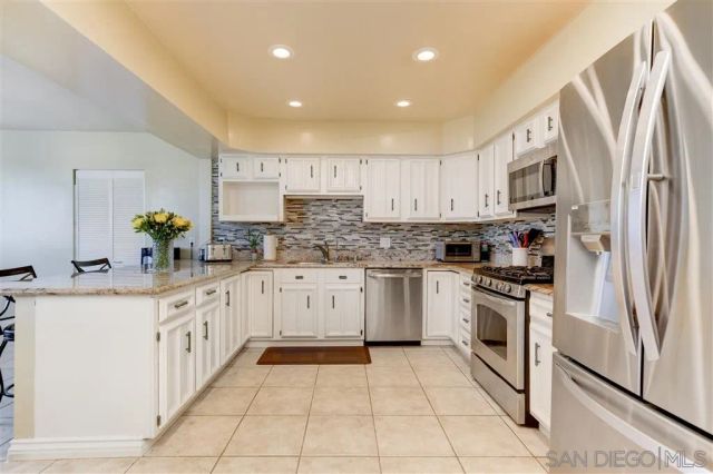 a large kitchen with stainless steel appliances granite countertop a stove a sink and a refrigerator