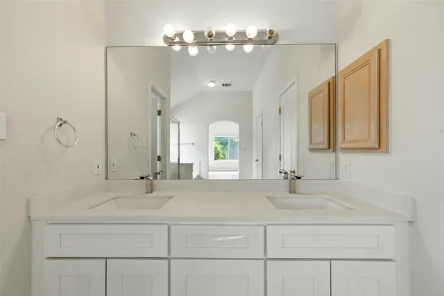 a bathroom with double vanity sinks a vanity a lamp and a mirror