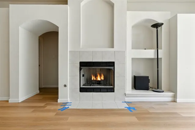 a view of an empty room with wooden floor and a fireplace