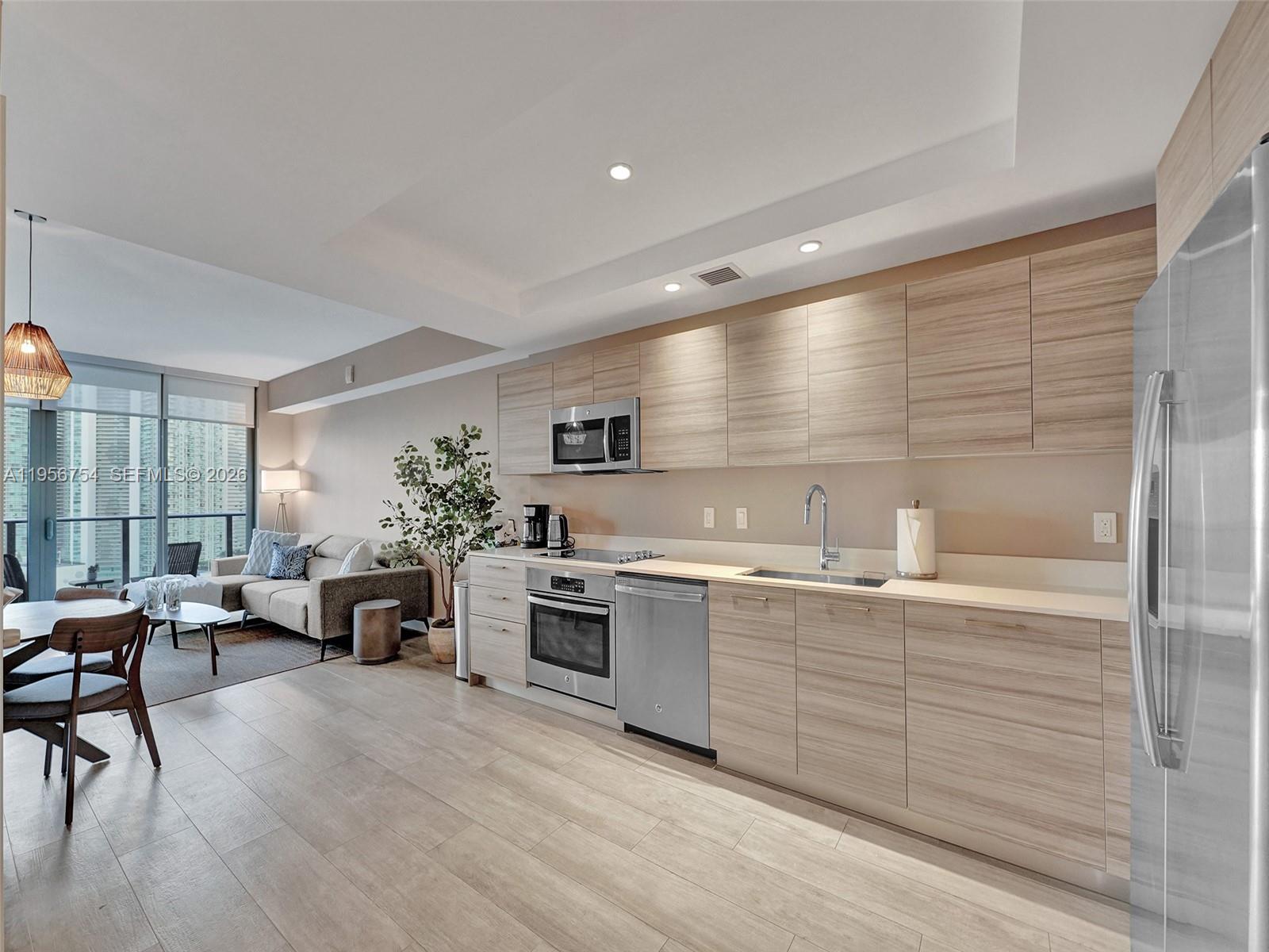 121 Northeast 34th Street, Unit 2106A Miami, FL 33137 - Photo 15 of 59 a large white kitchen with stainless steel appliances kitchen island granite countertop a large kitchen island a stove a sink dish washer and a granite countertops with cabinets