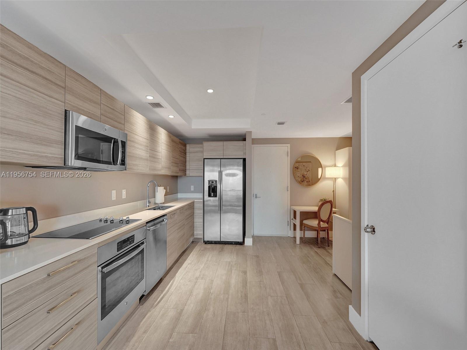 121 Northeast 34th Street, Unit 2106A Miami, FL 33137 - Photo 17 of 59 a large kitchen with a wooden floor and stainless steel appliances