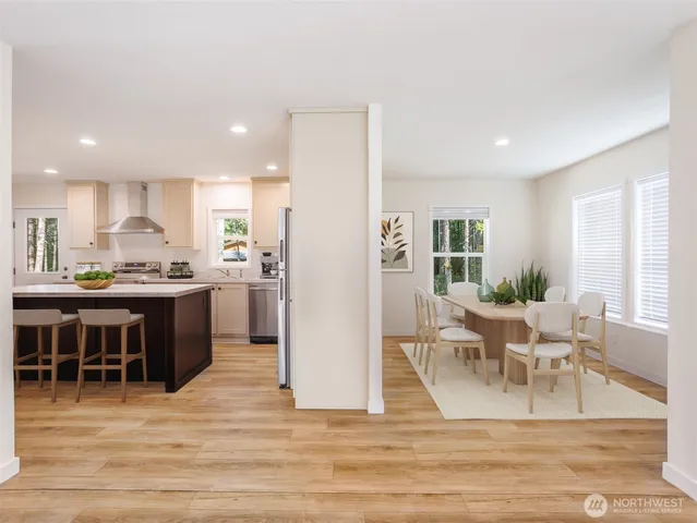 a view of kitchen with kitchen island stainless steel appliances wooden floor dining table and chair