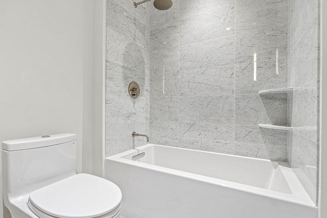 a white toilet sitting next to a bath tub