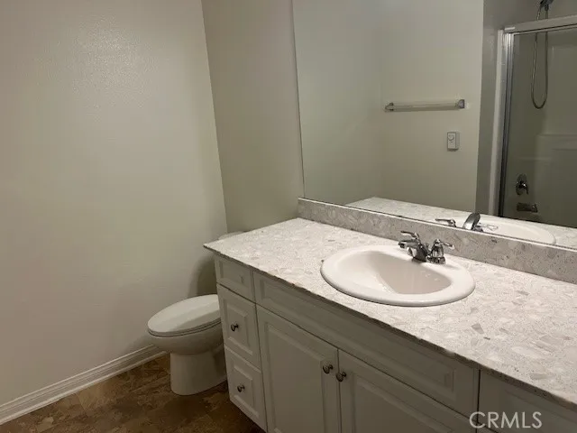 a bathroom with a granite countertop sink a toilet and a mirror