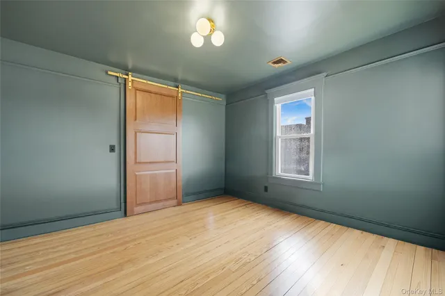 an empty room with wooden floor cabinet and windows
