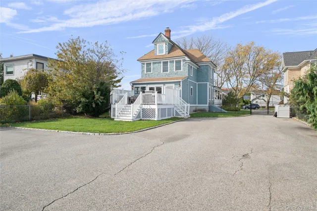 a view of a white house with a big yard and large trees