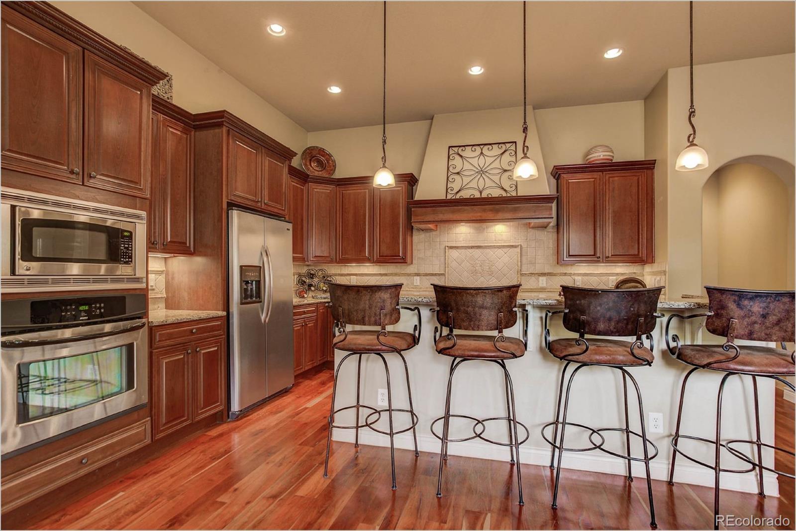 4363 Chateau Ridge Lane Castle Rock, CO 80108 - Photo 6 of 32 a open kitchen with stainless steel appliances granite countertop a refrigerator a stove top oven a sink island and chairs with wooden floor