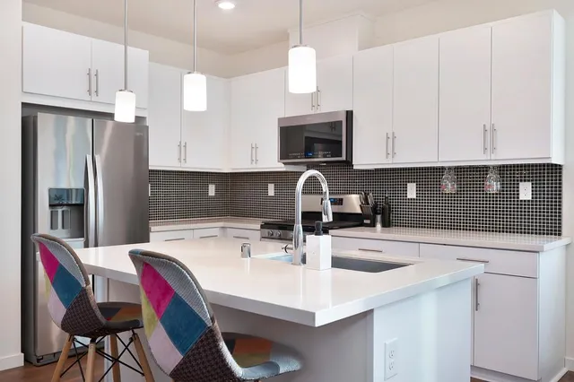 a kitchen with stainless steel appliances a sink a stove a refrigerator a center island and cabinets