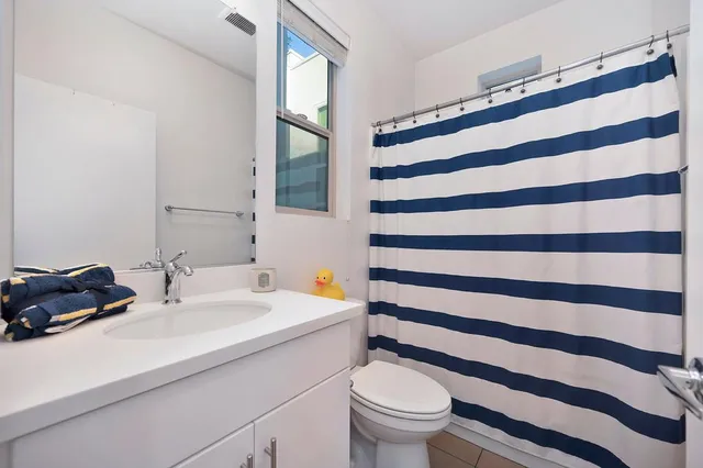 a bathroom with a sink a toilet a mirror and shower curtain