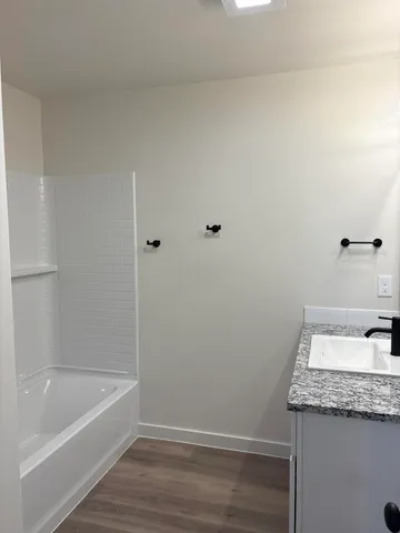 a bathroom with a granite countertop sink and white tub