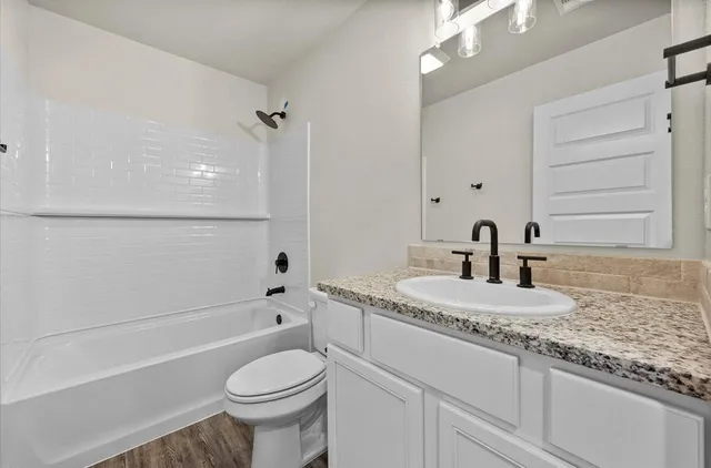 a bathroom with a granite countertop toilet sink and mirror