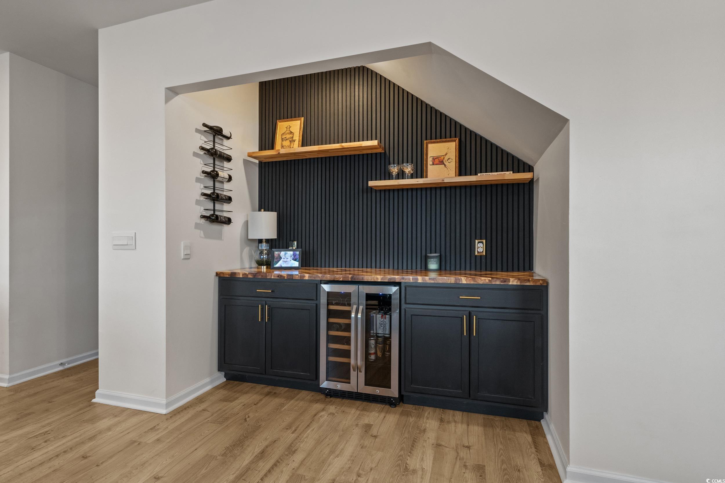 3343 Bells Lake Circle Longs, SC 29568 - Photo 10 of 40 Indoor dry bar with open shelves, beverage cooler, dark cabinetry, light wood-style floors, and dark stone countertops