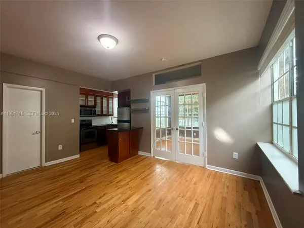 a view of an empty room with wooden floor and a window