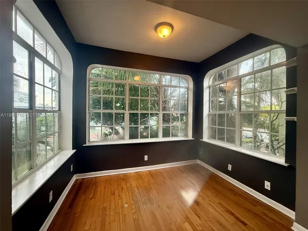 a view of an empty room with a window and wooden floor