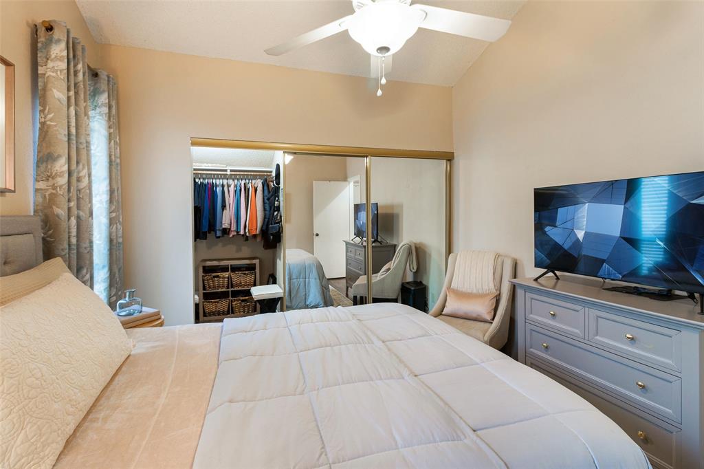 17490 Meandering Way, Unit 804 Dallas, TX 75252 - Photo 12 of 33 a bedroom with a large bed and a flat tv screen on dresser