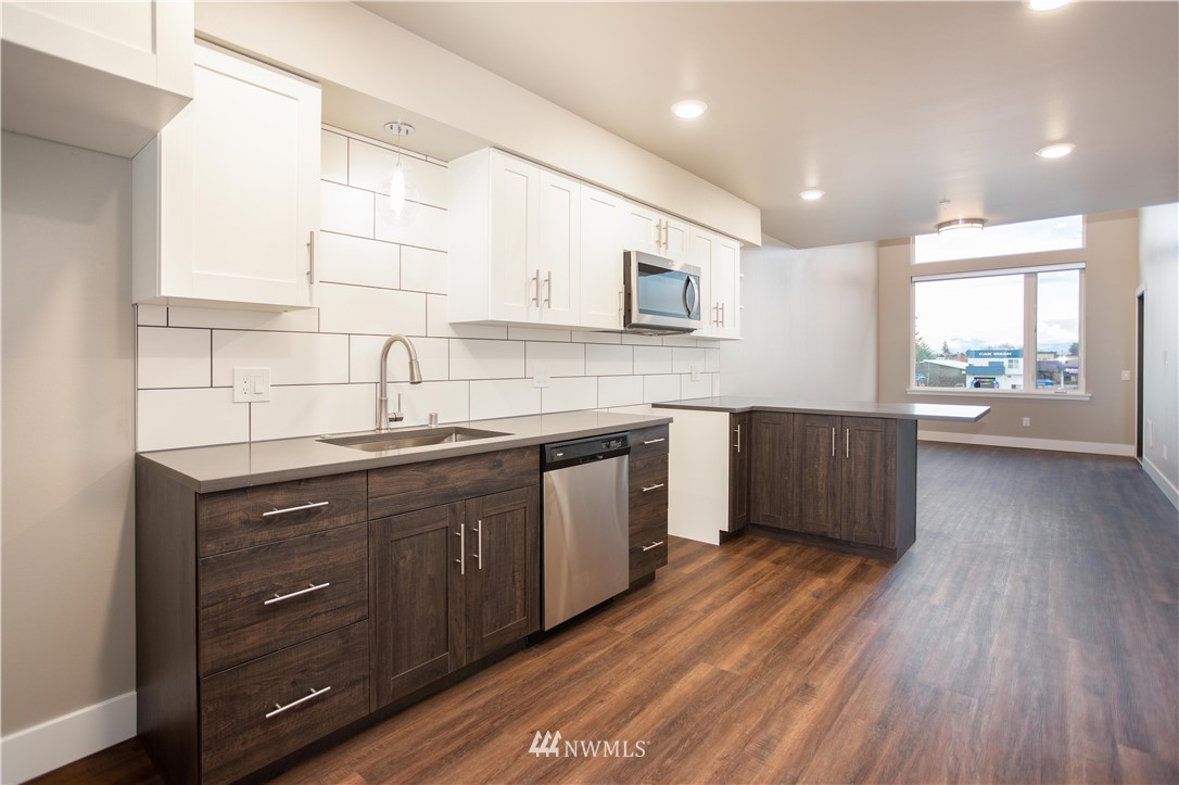 1880 Front Street, Unit 206 Lynden, WA 98264 - Photo 23 of 30 a kitchen with stainless steel appliances sink cabinets and wooden floor