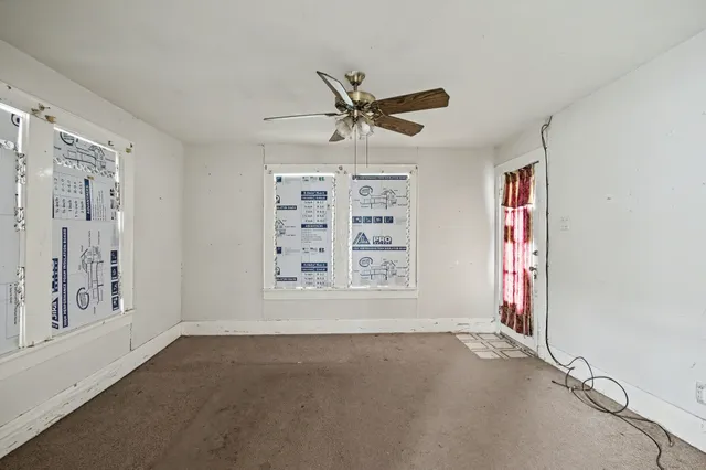 an empty room with windows and fan