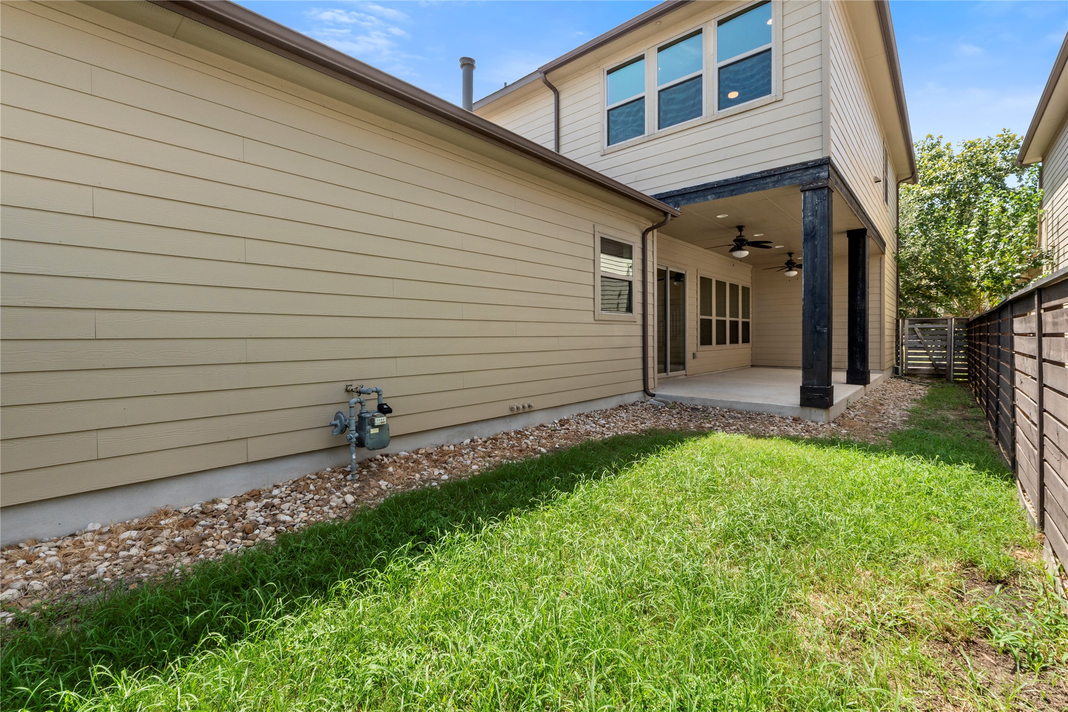 1709 Lawrence Street, Unit 5 Austin, TX 78741 - Photo 34 of 40 Horizontal lap siding pairs with a covered concrete patio adjacent to a grassy side yard.
