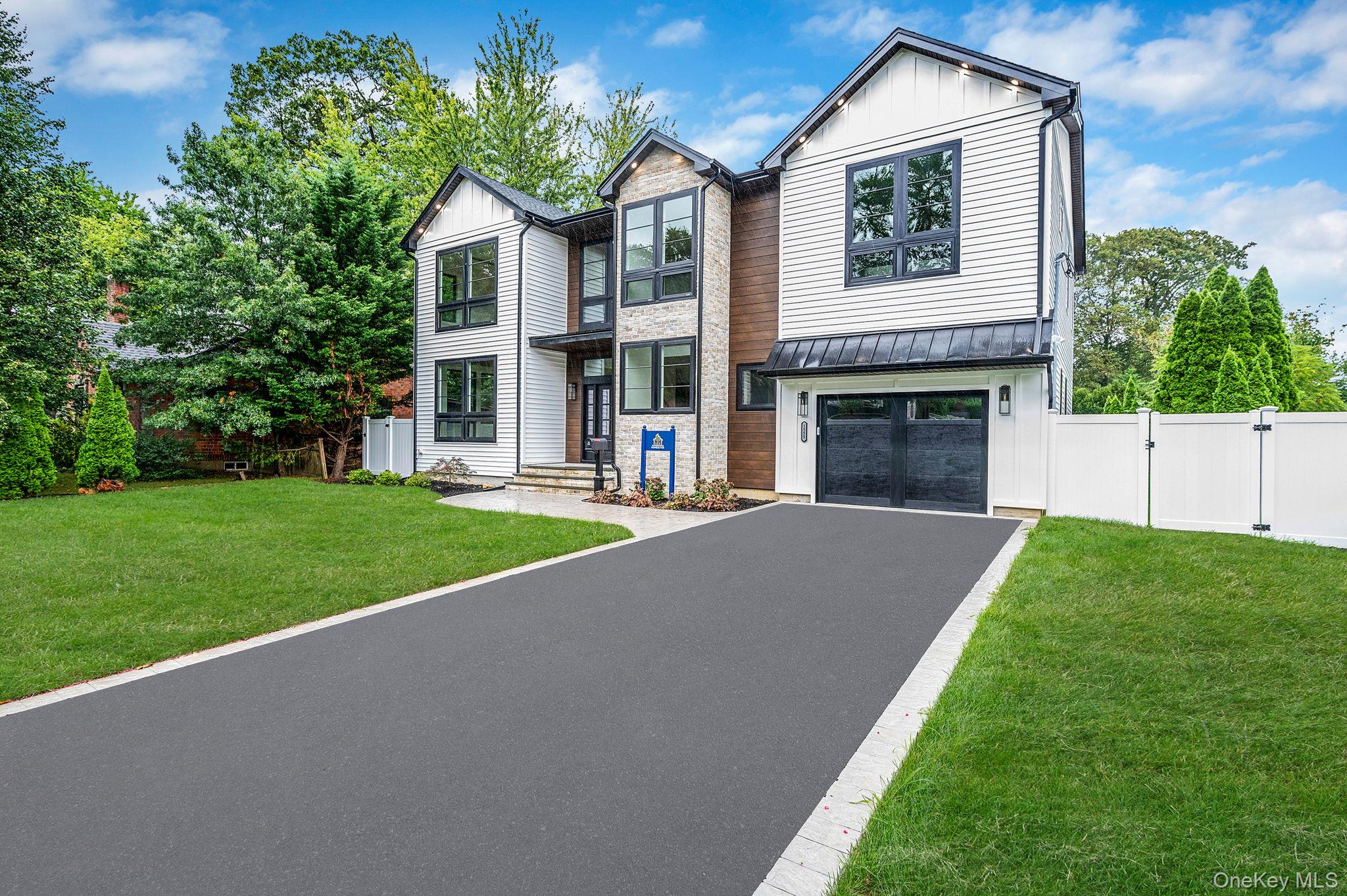 View of front of house with a gate, asphalt driveway, stone siding, an attached garage, and board and batten siding