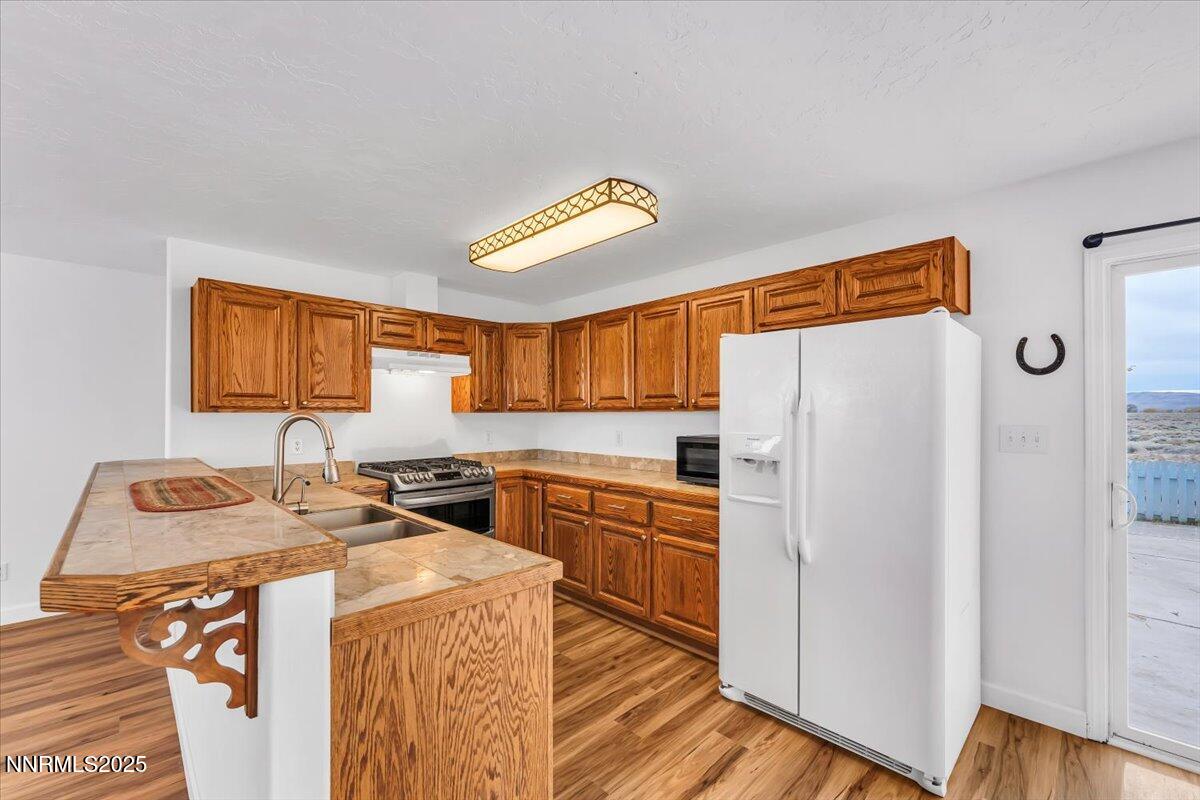 988 Bench Road Fallon, NV 89406 - Photo 10 of 54 a kitchen with a refrigerator a stove and wooden floor
