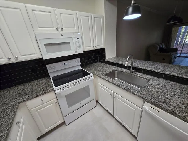 a kitchen with granite countertop white cabinets and a sink
