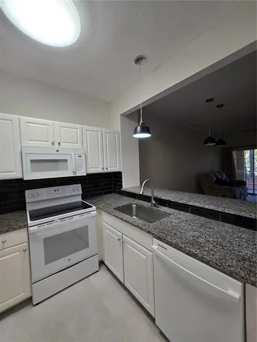 a kitchen with granite countertop white cabinets and white appliances