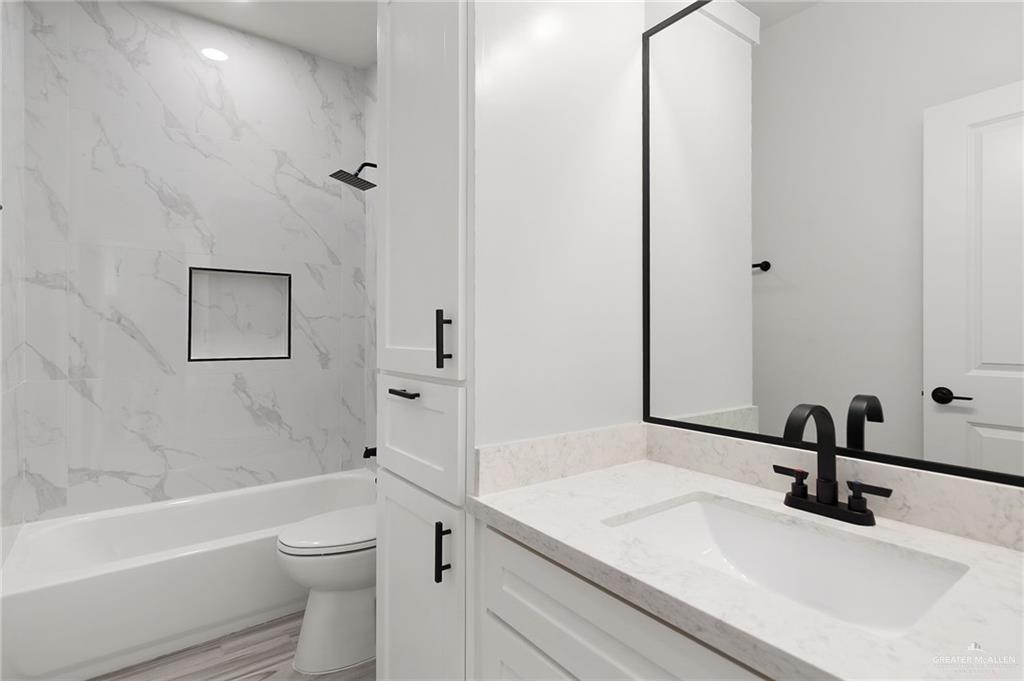 518 East E Loop, Unit 7 Harlingen, TX 78550 - Photo 9 of 14 a bathroom with a sink a toilet and a large mirror