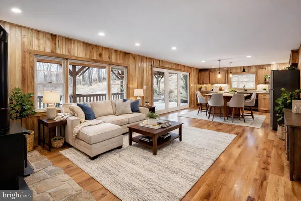 a living room with furniture two large window and a table