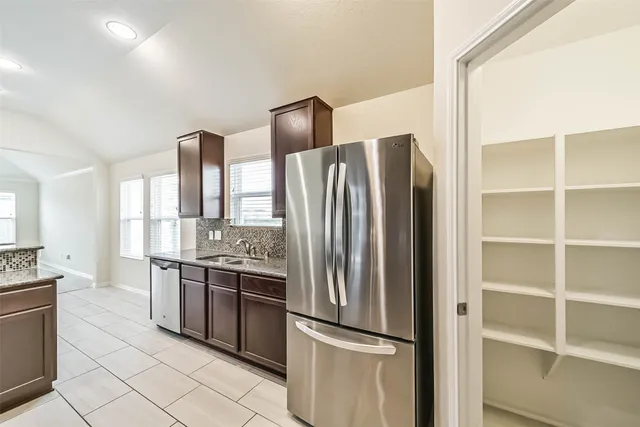 a kitchen with stainless steel appliances granite countertop a refrigerator and a stove top oven