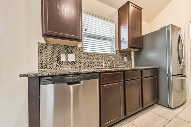 a kitchen with stainless steel appliances granite countertop a sink and a refrigerator