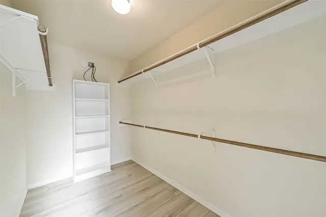 a view of an empty walk in closet with wooden floor
