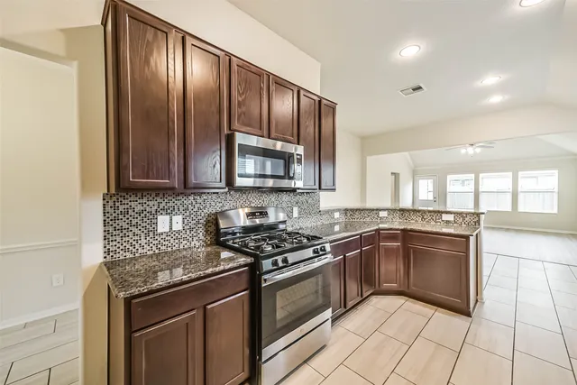 a kitchen with stainless steel appliances granite countertop a sink stove and microwave